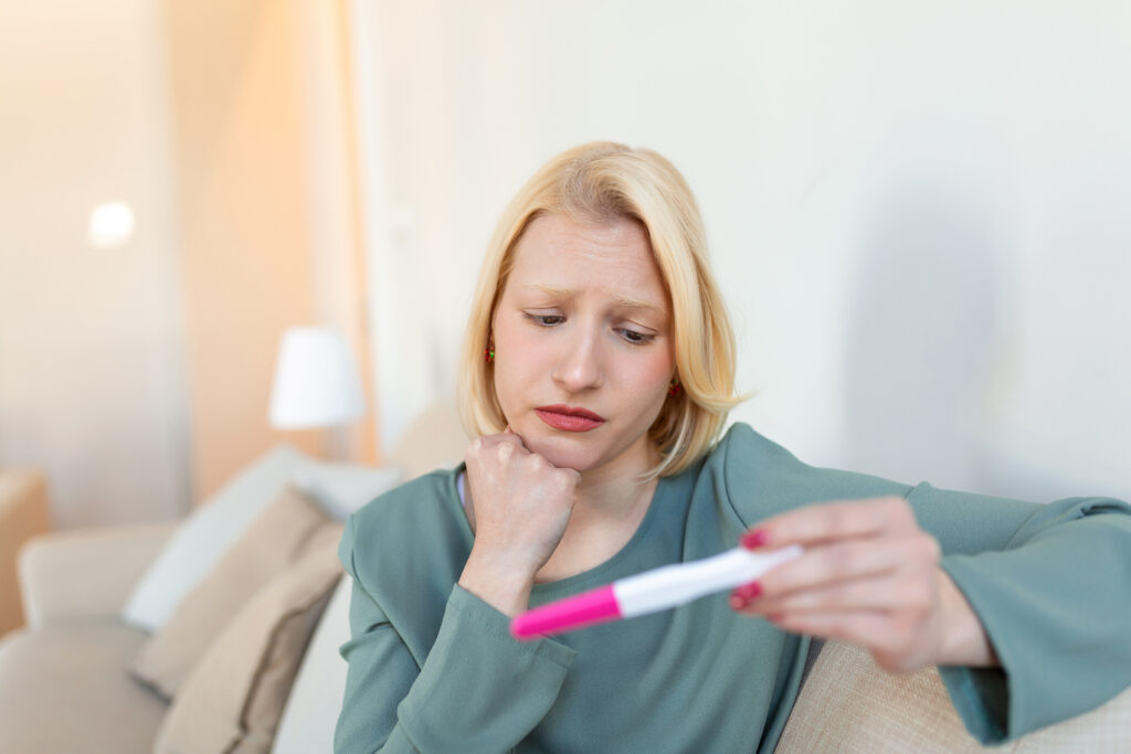 a woman looking at a pregnancy test after ovulation